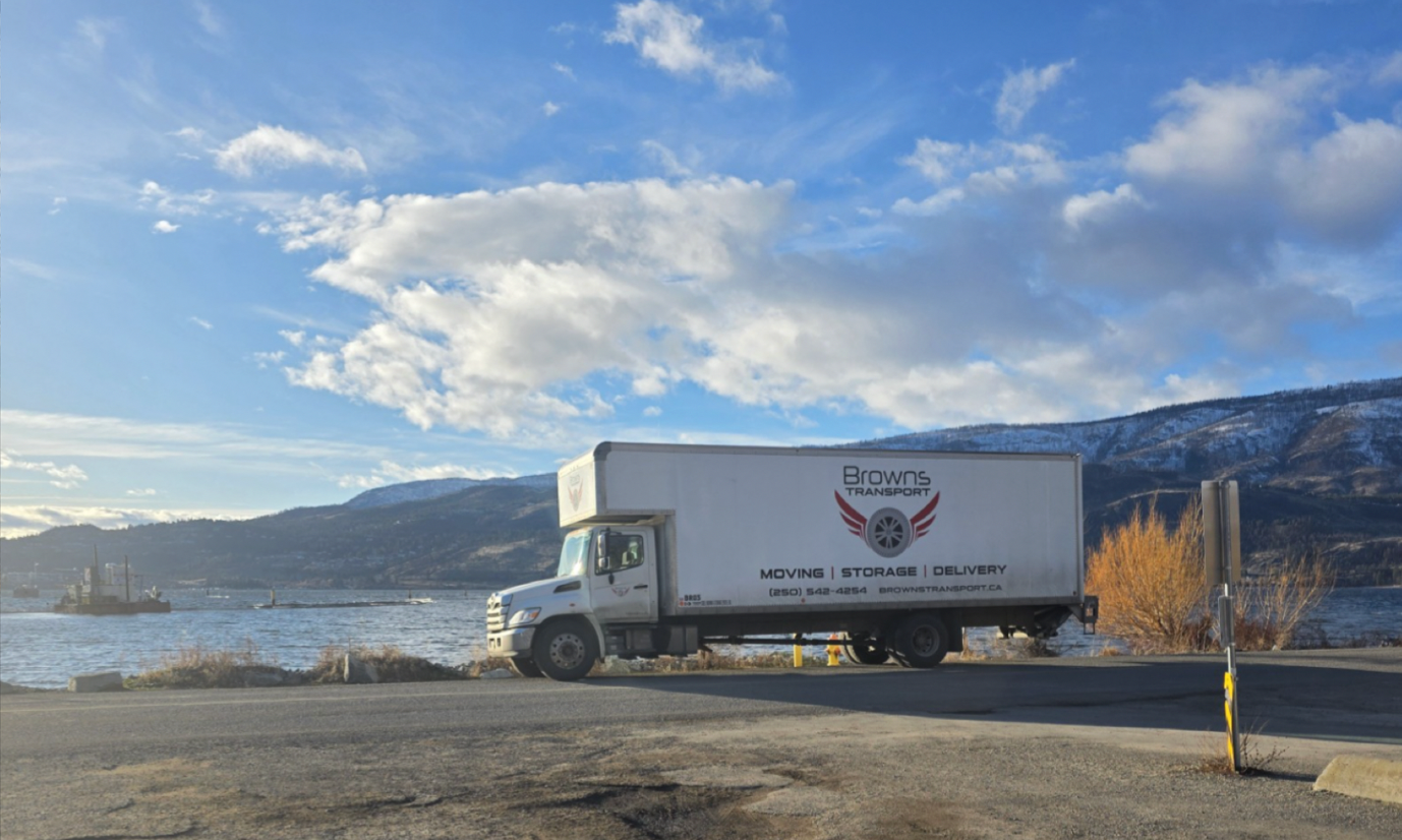 Browns Transport 5-ton moving truck parked by the water in Lake Country, providing household and commercial moving, household packing, and hot shot flat deck services.